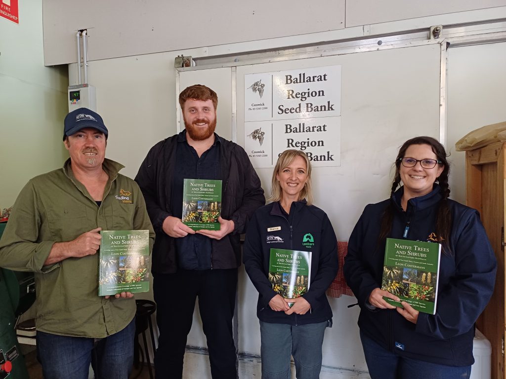 Four people holding books at Ballarat Region Seed Bank.