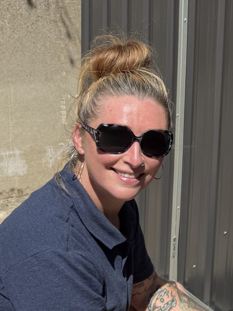 Person smiling, wearing sunglasses outdoors.